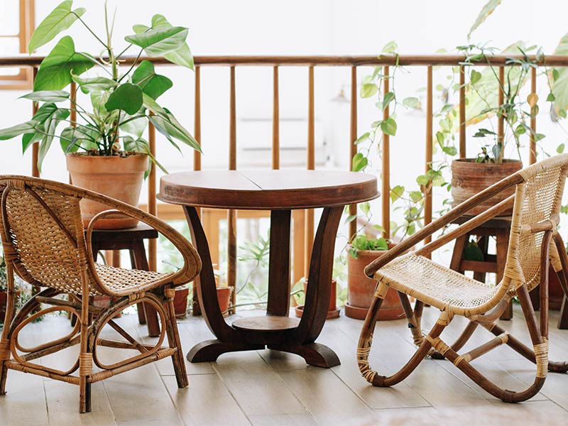 Cozy balcony furniture setup with cane chair & wooden center table - Beautiful Homes