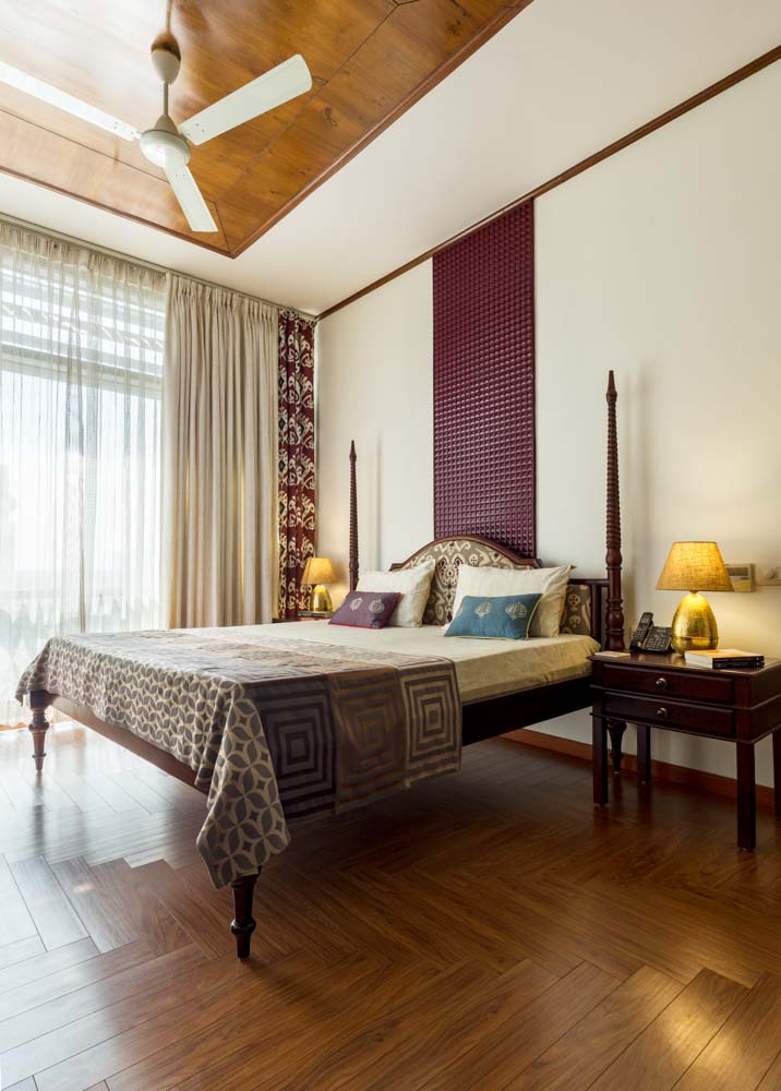 Simple bedroom design with a high four poster bed & wooden flooring - Beautiful Homes