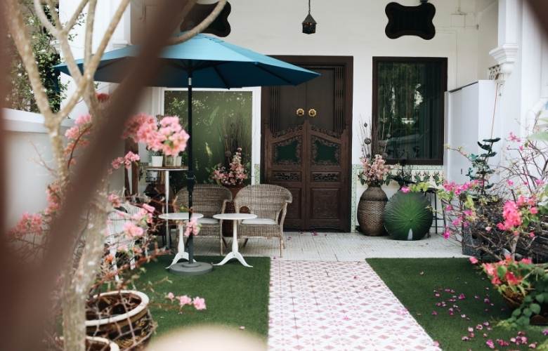 Home verandah with big umbrella over seating area & seasonal plants - Beautiful Homes