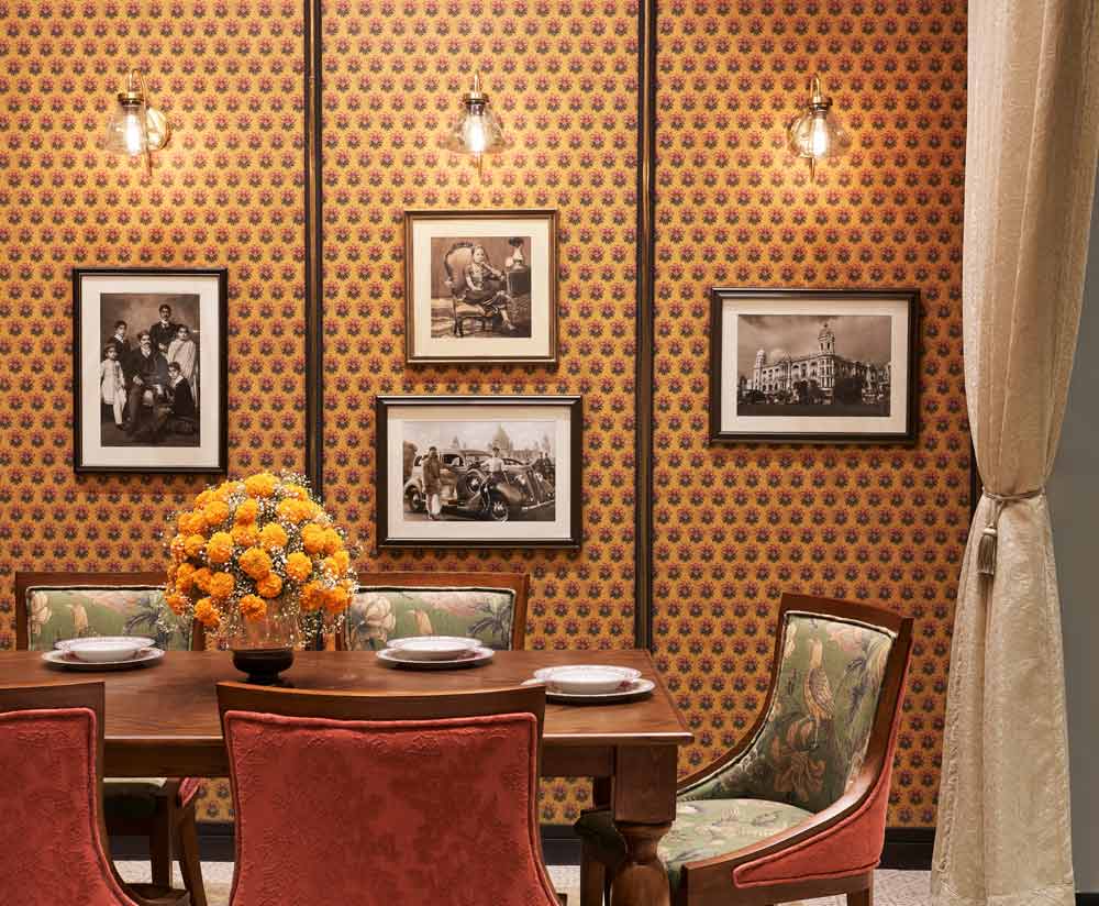 A dining room with an orange wallpaper and artworks with accent lights A dining room with an orange wallpaper and artworks with accent lights