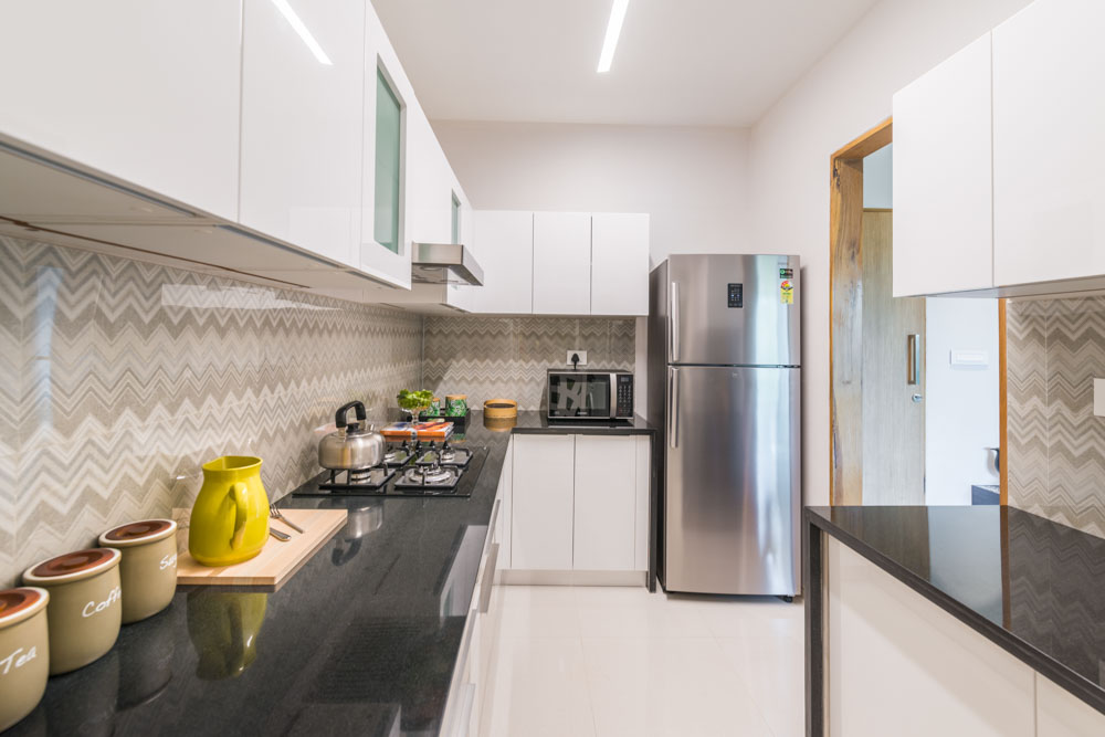 An all white modular kitchen design paired with patterned kitchen backsplash - Beautiful Homes
