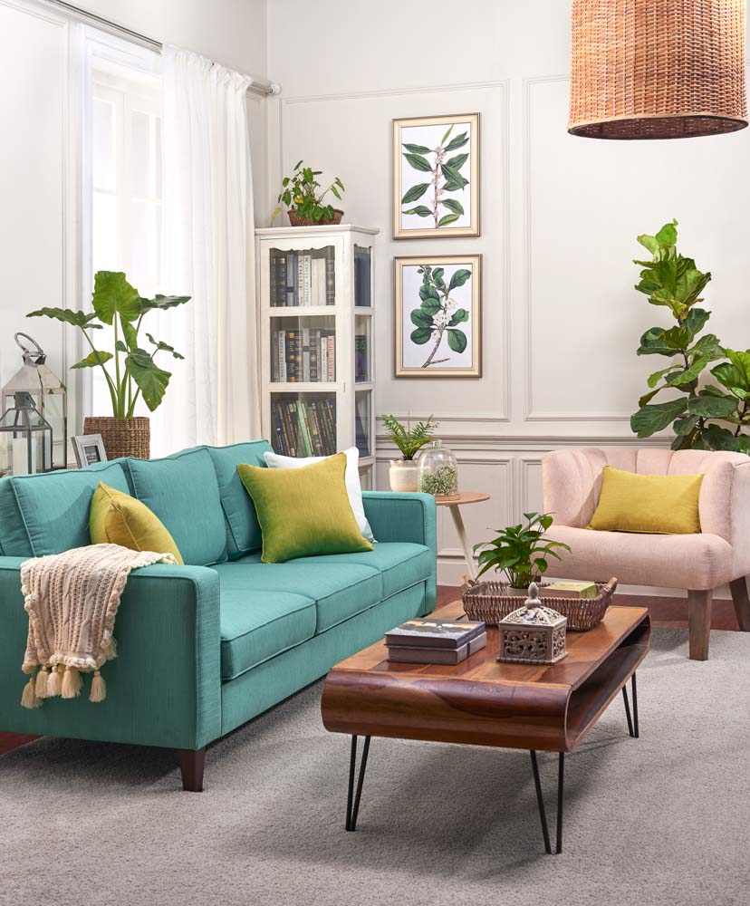 A turquoise coloured sofa with green cushions and a throw