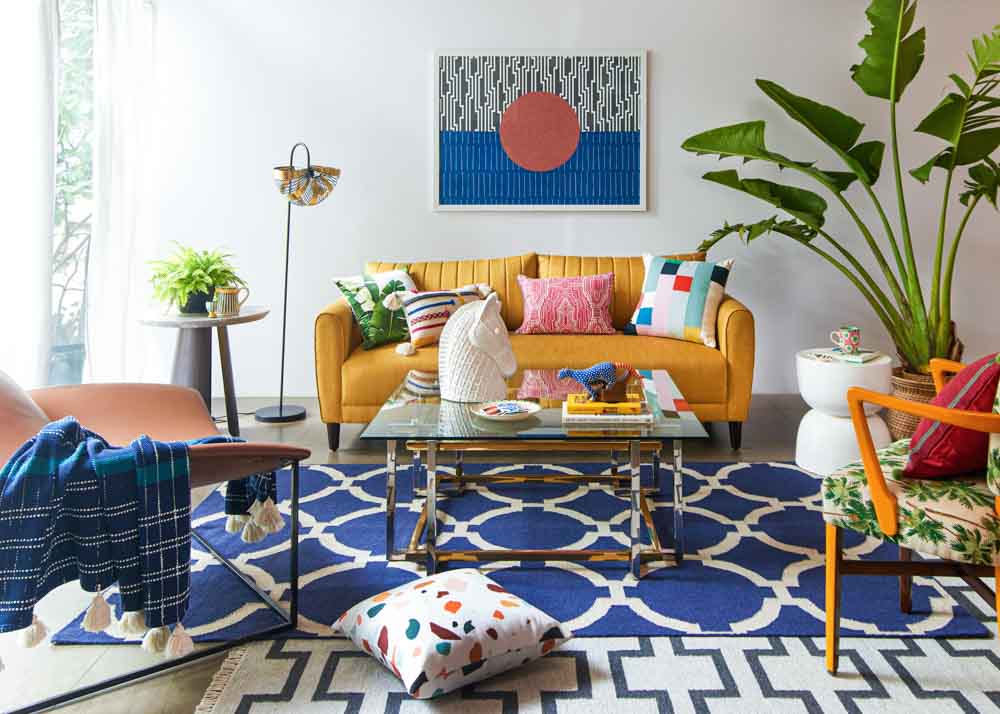 A Living room setting with a yellow sofa, coffee table, lamp and artwork