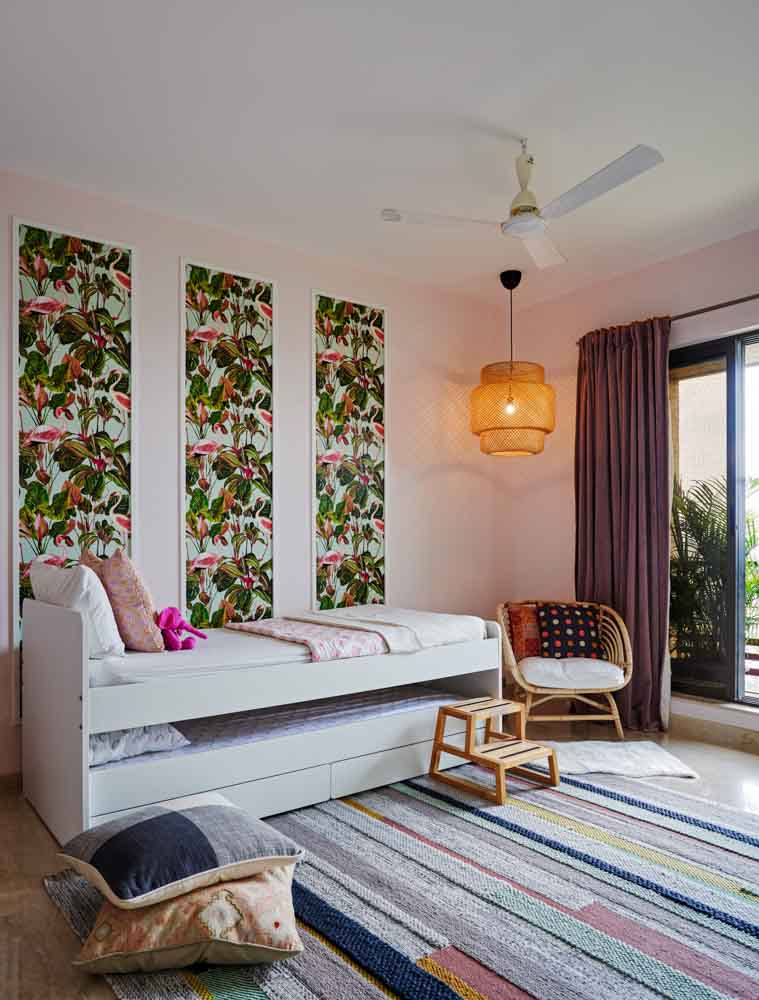 A kids room with a Trundle bed, and colourful artwork on the wall behind