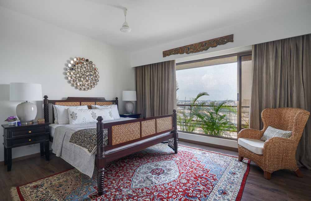 A bedroom with a large rug, a wooden bed in dark wood and two bedside tables