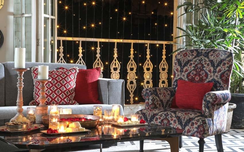 A living room with sofa, armchair and a balcony decorated with lights