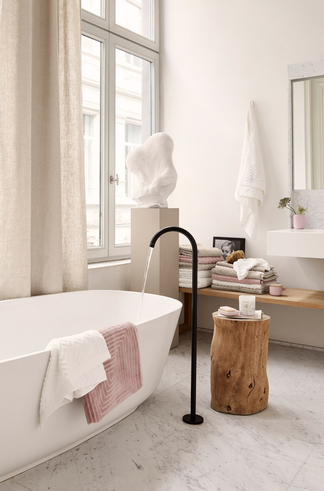 Bathroom with art pieces, towels and other accessories in pastel shades such as white, pink and grey 