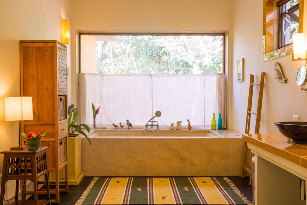 Earthy bathroom accessories in a bathroom open to the outside with a big window