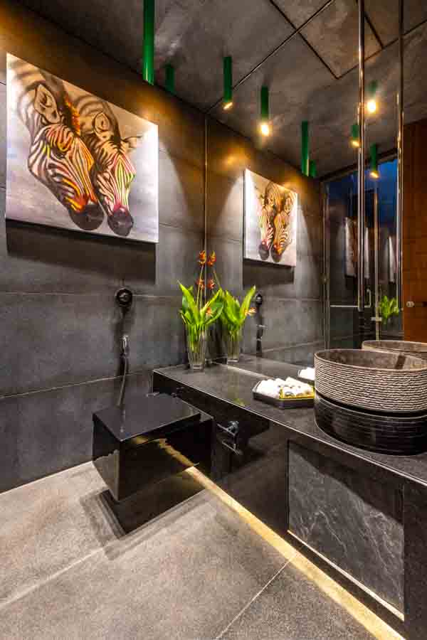 Bright green bamboo shaped bathroom ceiling lights in a dark bathroom, flowers in a vase and wildlife art