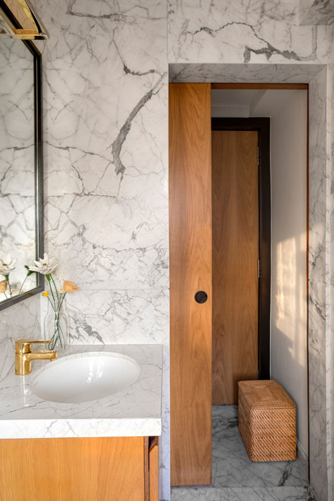 Small washroom design with white marble walls and wooden doors