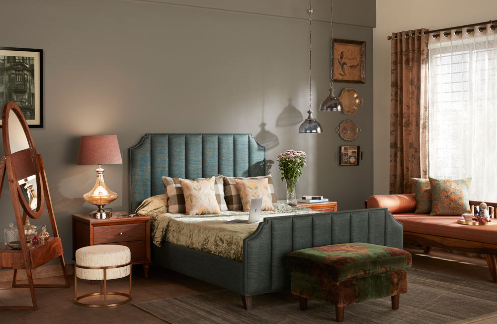  A bedroom with a green bed, a couple of side tables, a wooden framed mirror and a sofa