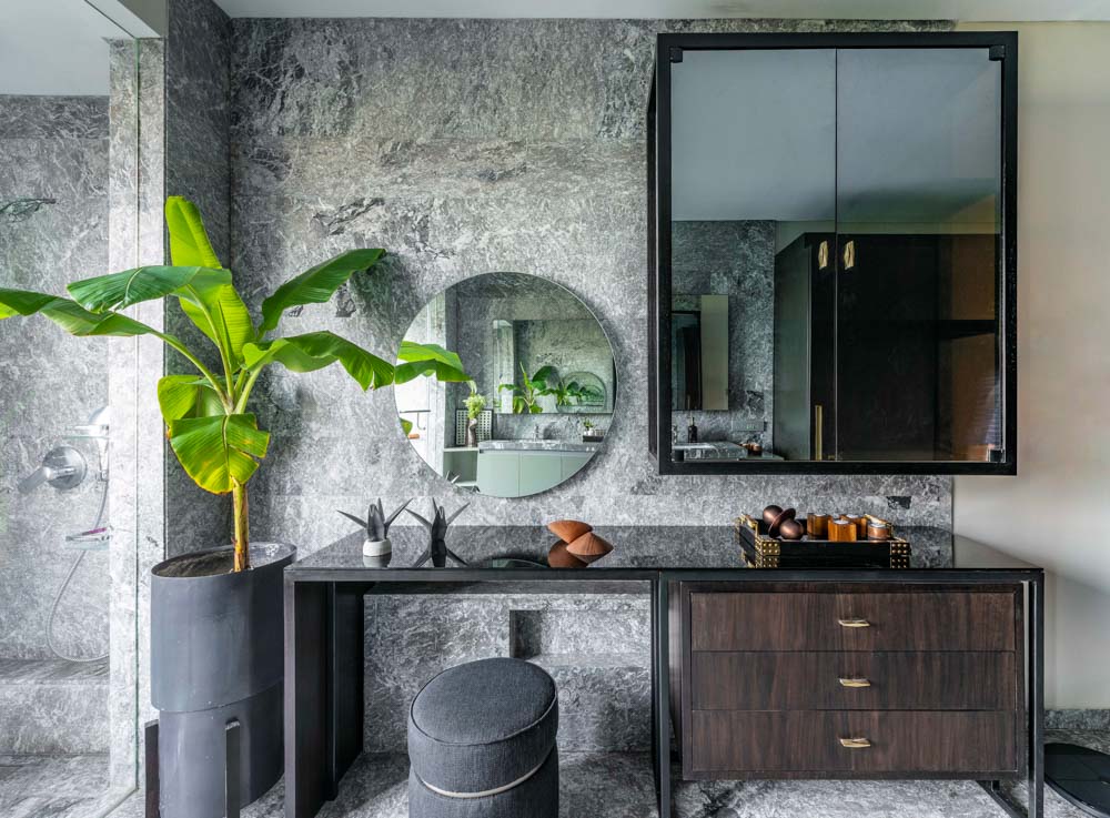 Dressing table with mirror in black modern bedroom design against granite wall with banana plant - Beautiful Homes