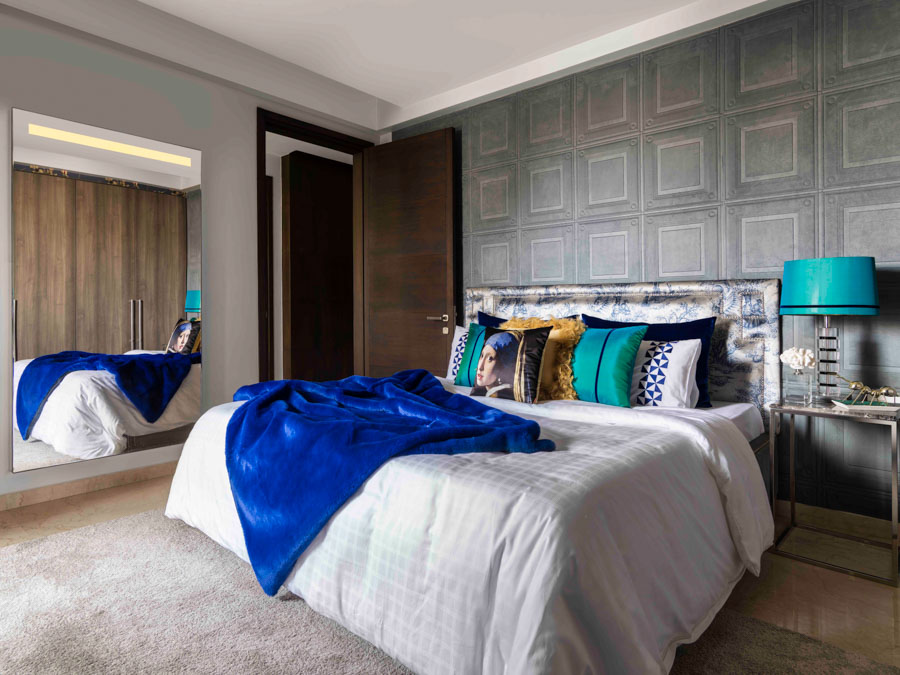 Modern bedroom design with blue touches for a livelier atmosphere, patterned headboard and colourful cushions