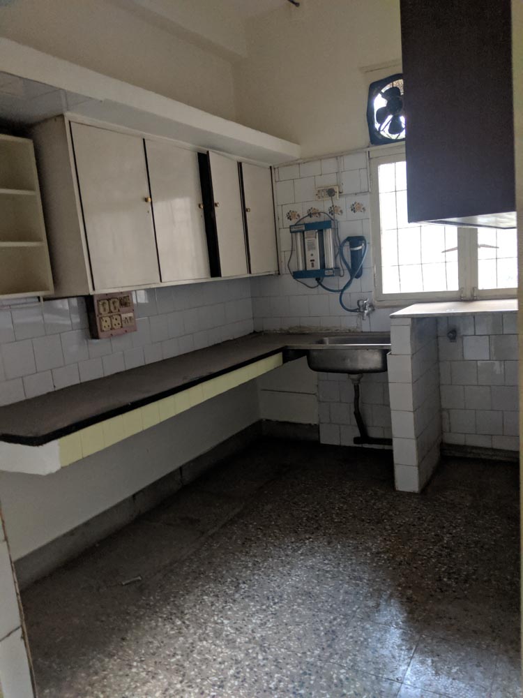 Kitchen interiors with dark terrazzo flooring,  white tiles & dark kitchen countertop - Beautiful Homes