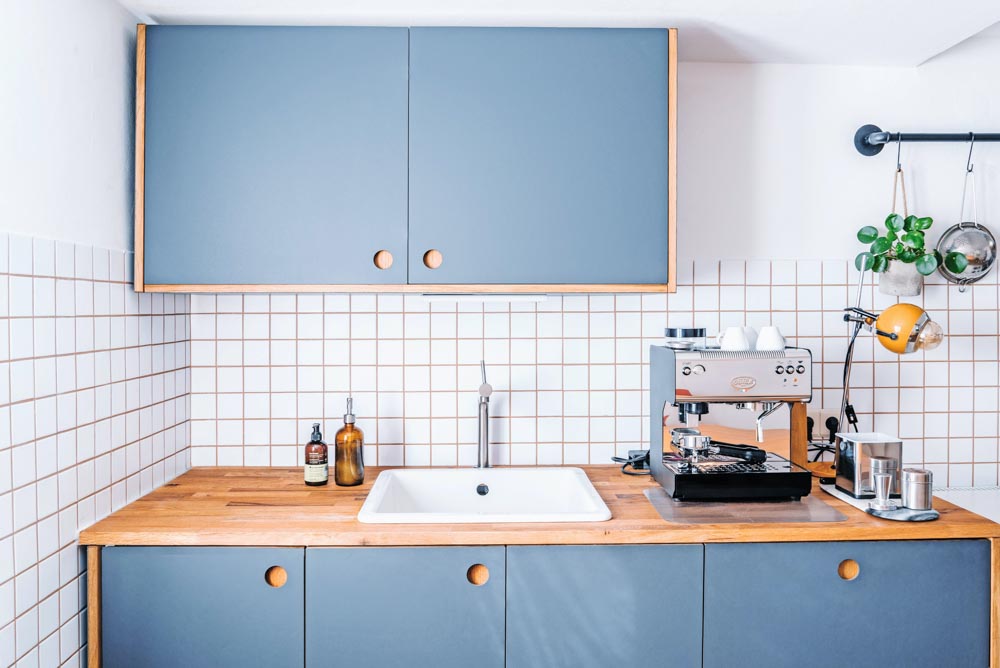Modular kitchen design with pastel blue & white shades along with wooden kitchen countertop - Beautiful Homes