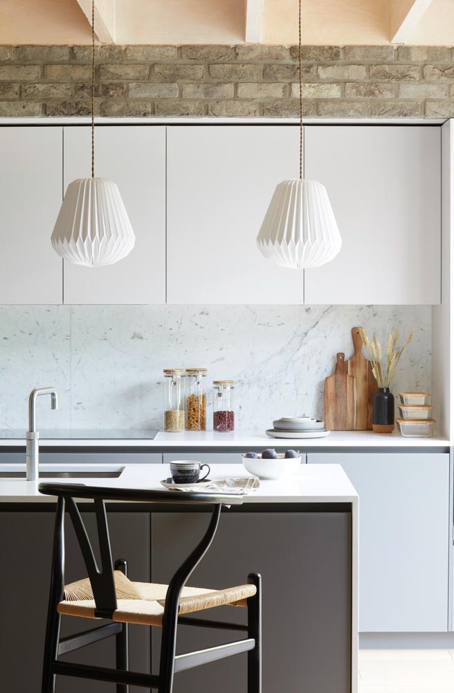 A modular kitchen with textured wall & white coloured cabinets with pendant lights cabinets - Beautiful Homes