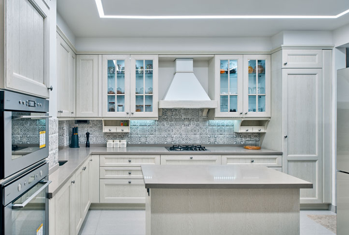 A well organised spacious modular kitchen with tiled wall & solid white cabinets with a touch of blue colour - Beautiful Homes