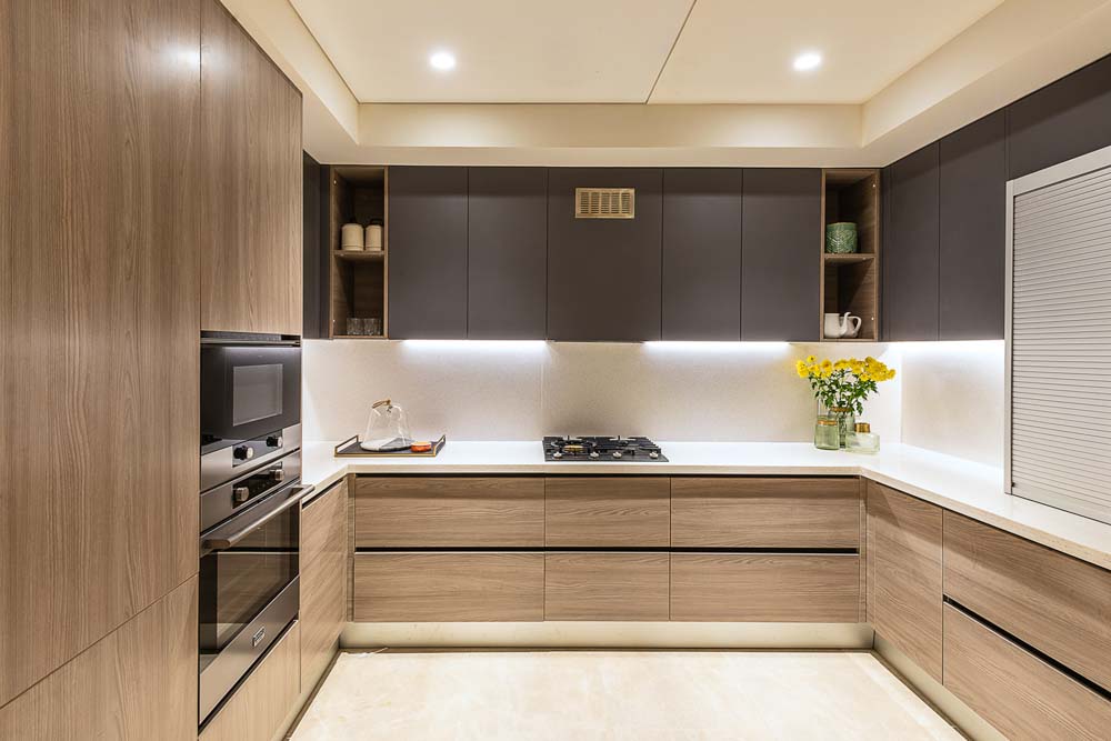 Light finish wood veneer & white countertop in this u shaped modular kitchen design - Beautiful Homes